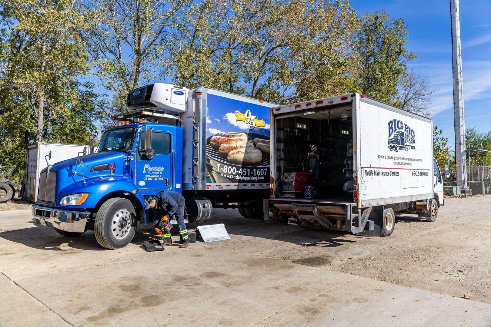 Big Rig Fixer technician servicing a refrigerated box truck next to the Big Rig Fixer mobile service truck
