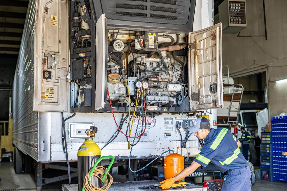 Technician recharging a trailer refrigeration unit in the shop