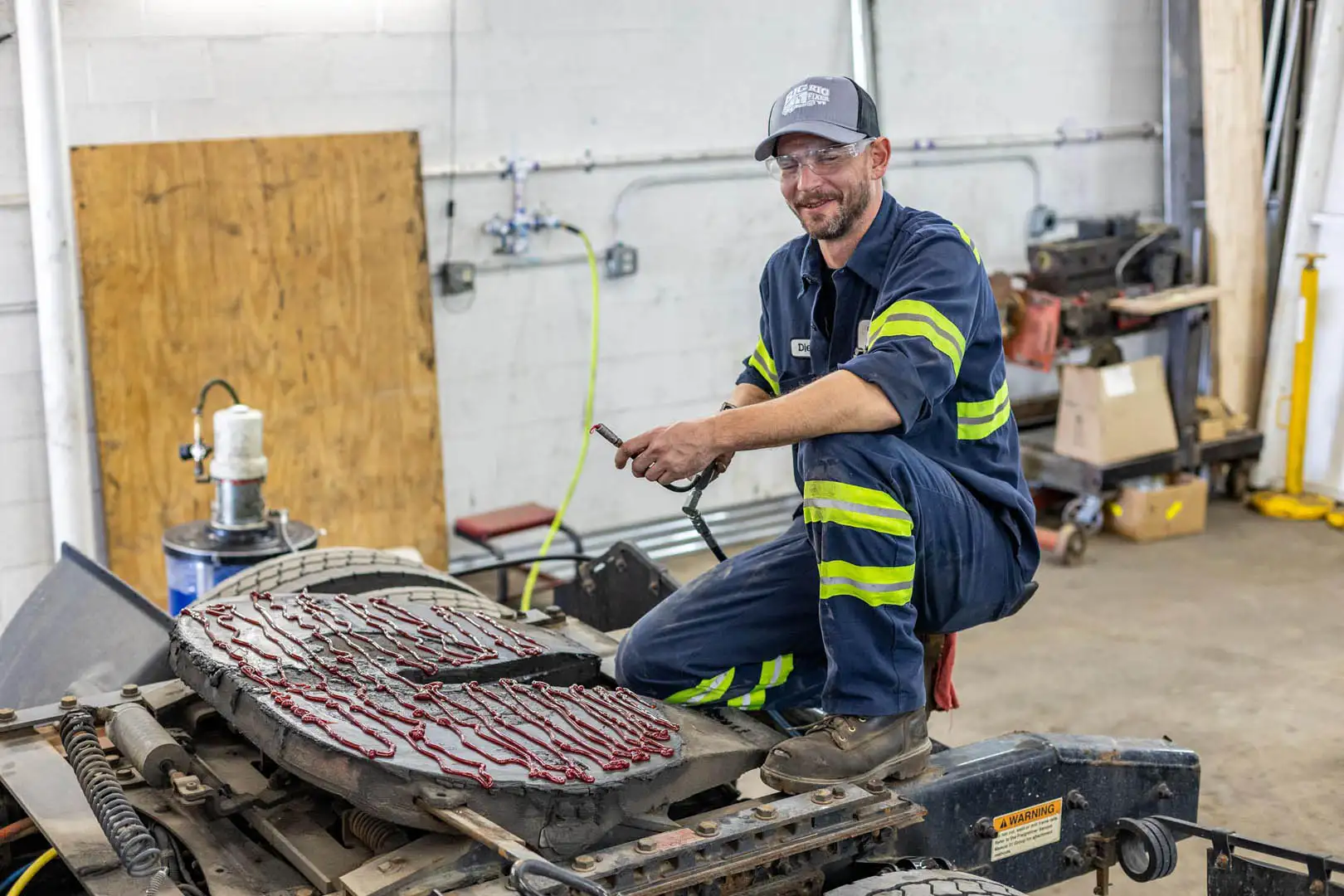 Technician greasing truck fifth wheel